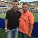 Tom Cavalli posing for picture with Jarod Borgetti in a soccer stadium