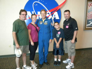 Tom and Leigh Cavalli and friends posing with astronaut in front of a NASA sign