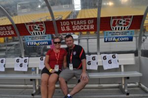 Tom and Leigh Cavalli sitting on the team bench in an empty soccer stadium