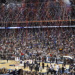 Connecticut Basketball team celebrating victory in stadium with confetti blasts.